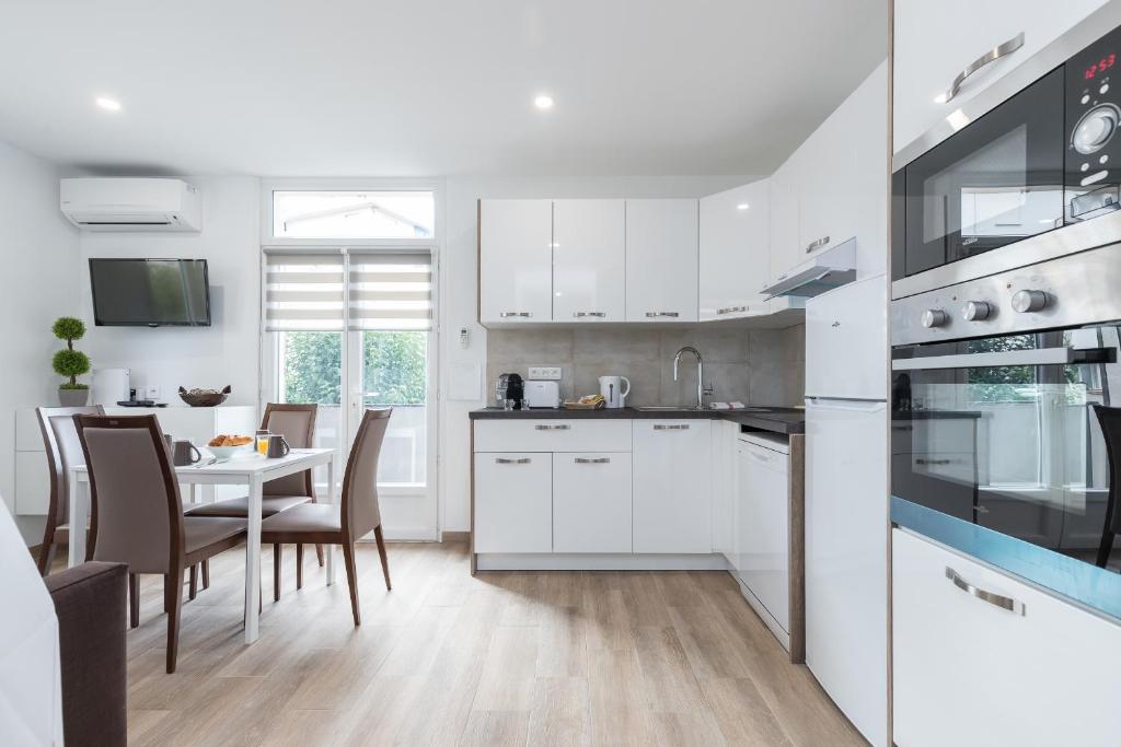 a kitchen with white cabinets and a table with chairs at Sleep in Antibes City Port in Antibes