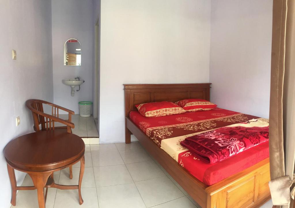 a bedroom with a bed and a chair and a table at Homestay Lereng Bromo in Bromo