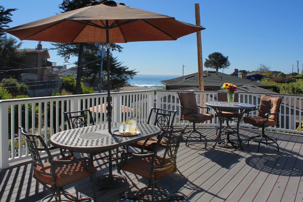 eine Terrasse mit Tischen, Stühlen und einem Sonnenschirm in der Unterkunft Ocean Echo Inn & Beach Cottages in Santa Cruz