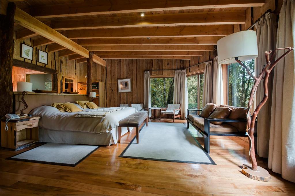 um quarto com uma cama, um sofá e uma mesa em Huilo Huilo Nawelpi Lodge em Huilo Huilo