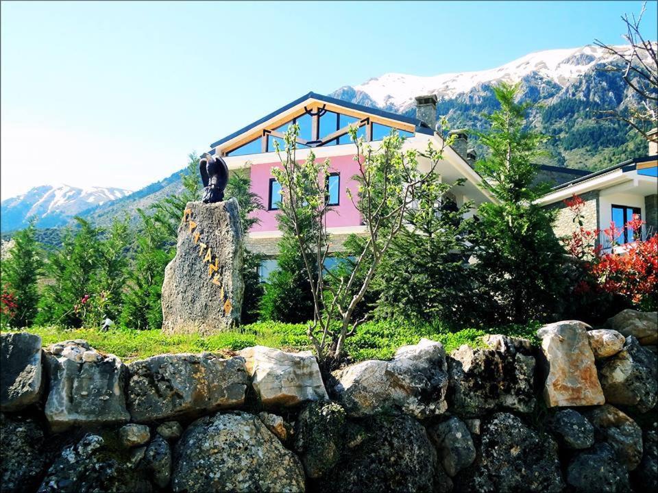 una casa rosa detrás de una pared de piedra delante de una casa en Prytaneio Design Hotel, en Dodoni