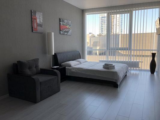 Apartmant in Smart Plaza في كييف: غرفة نوم بسرير وكرسي ونافذة