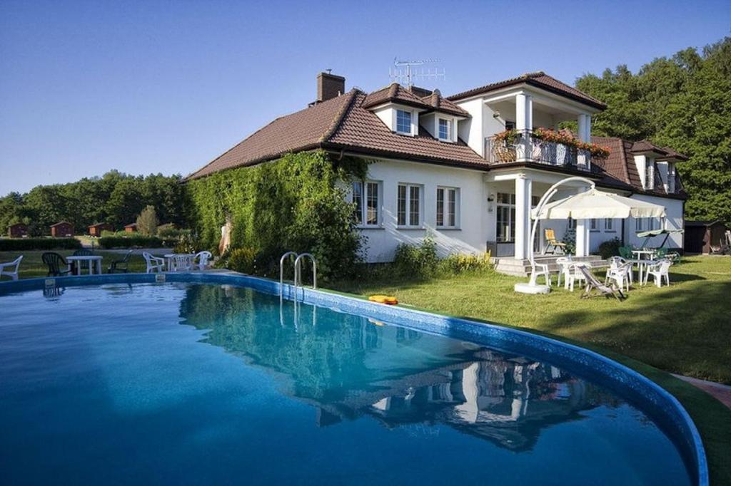 a large swimming pool in front of a house at Leśny Dworek Winnica Darłowo in Darłowo