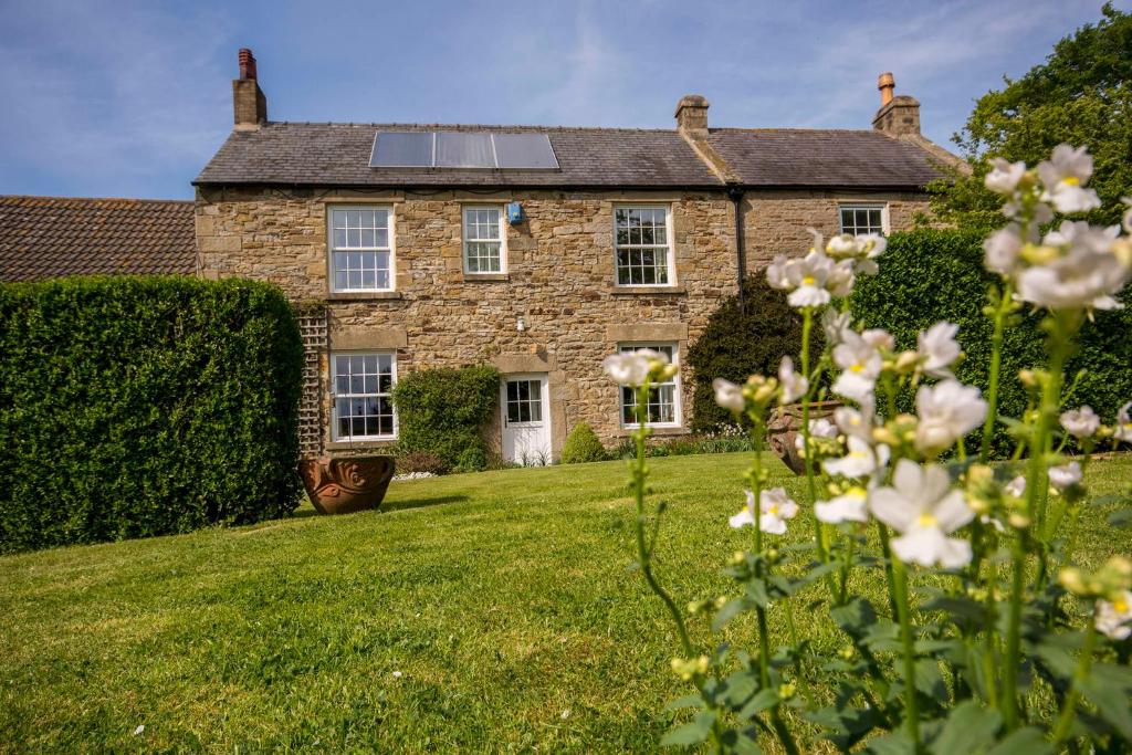 una antigua casa de piedra con paneles solares en el techo en Rye Hill Farm, en Hexham