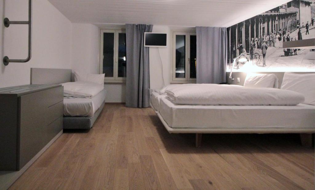 a bedroom with two beds and a dresser in it at Hotel & Restaurant Forni in Airolo