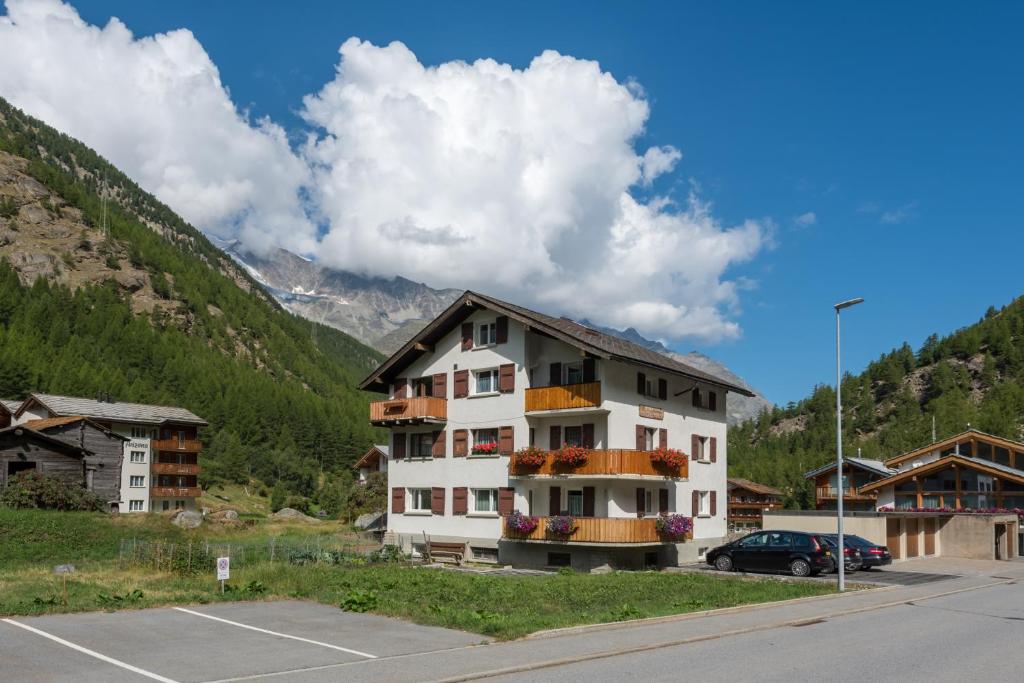 a building in a parking lot next to a mountain at Haus Bergsonne in Saas-Almagell