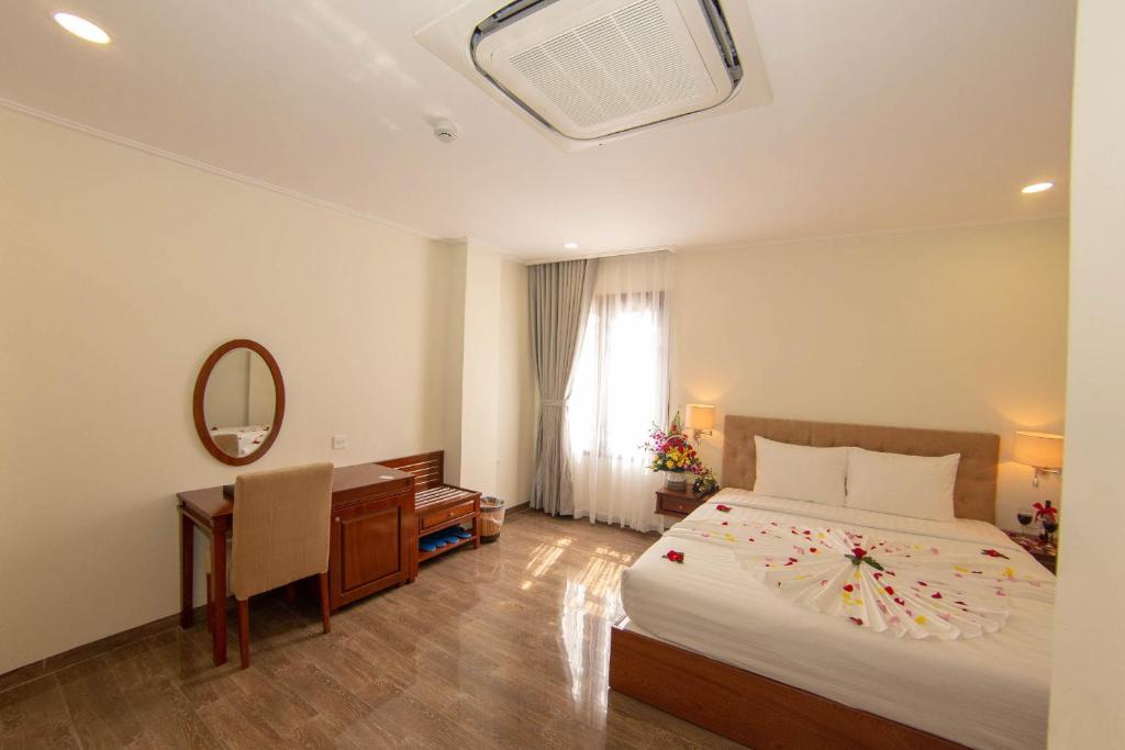 a bedroom with a bed and a desk and a mirror at Trường Hải Hotel in Nha Trang