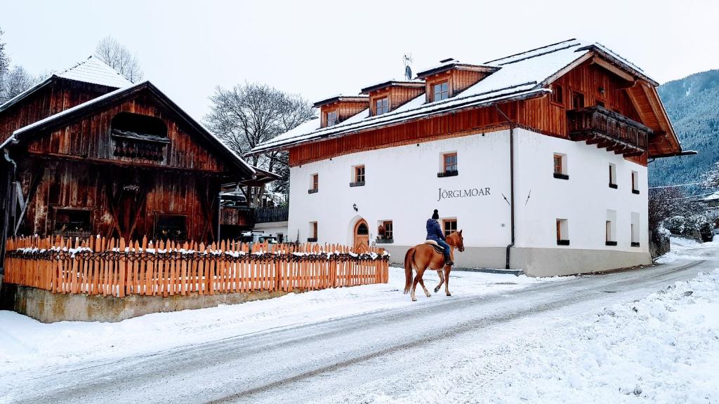 una persona montando un caballo en la nieve al lado de un edificio en Jörglmoar, en San Lorenzo di Sebato