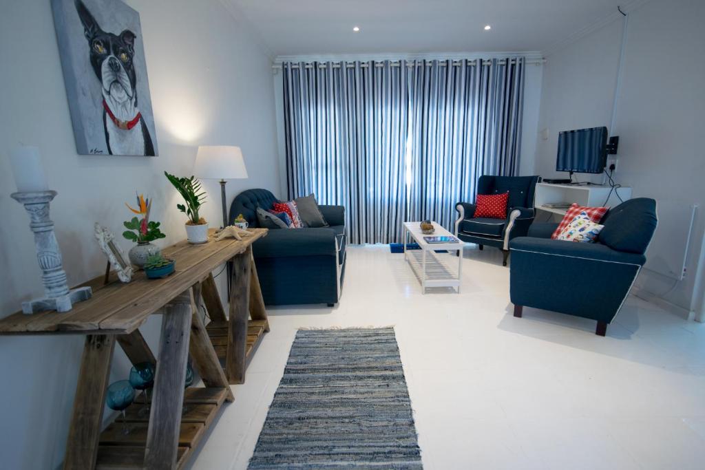 a living room with a wooden table and blue chairs at Leisure By The Sea in Kleinmond