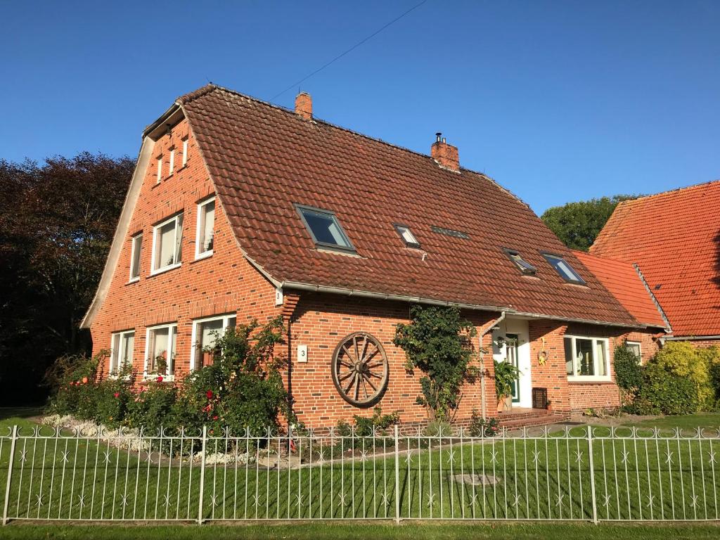 una casa de ladrillo con un reloj a un lado. en Mehr -Nordseeurlaub, en Butjadingen