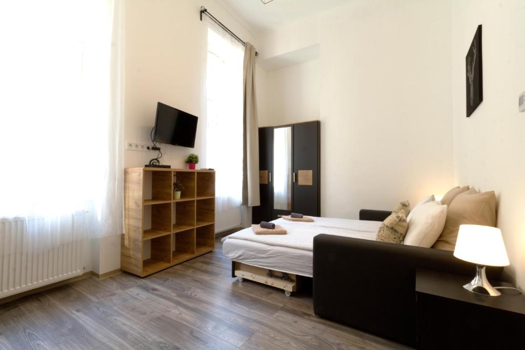 a bedroom with a bed and a couch and a television at Karikum Small in Budapest