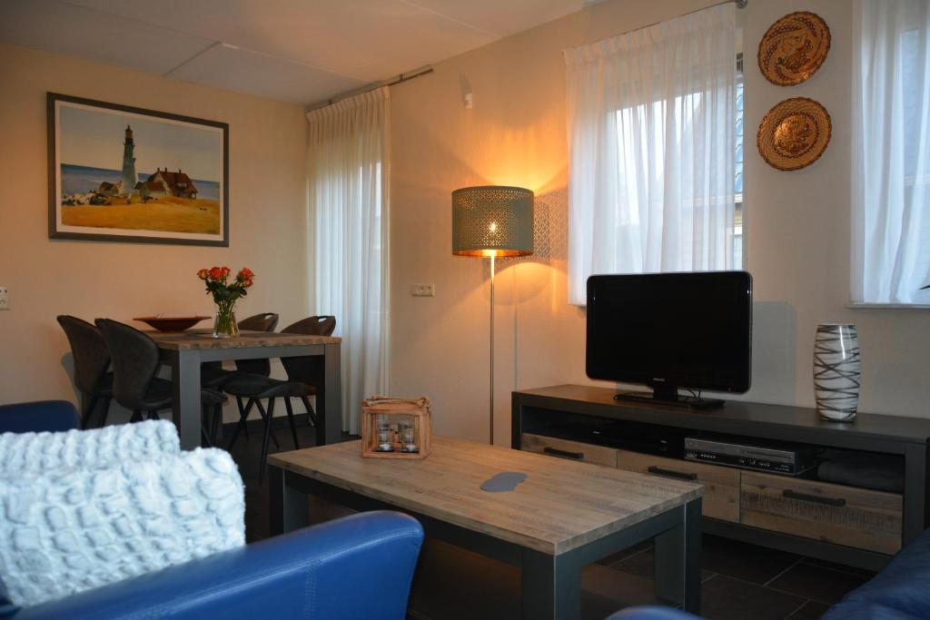 a living room with a tv and a blue couch at Appartement Derde Zandwijkje in Hollandscheveld