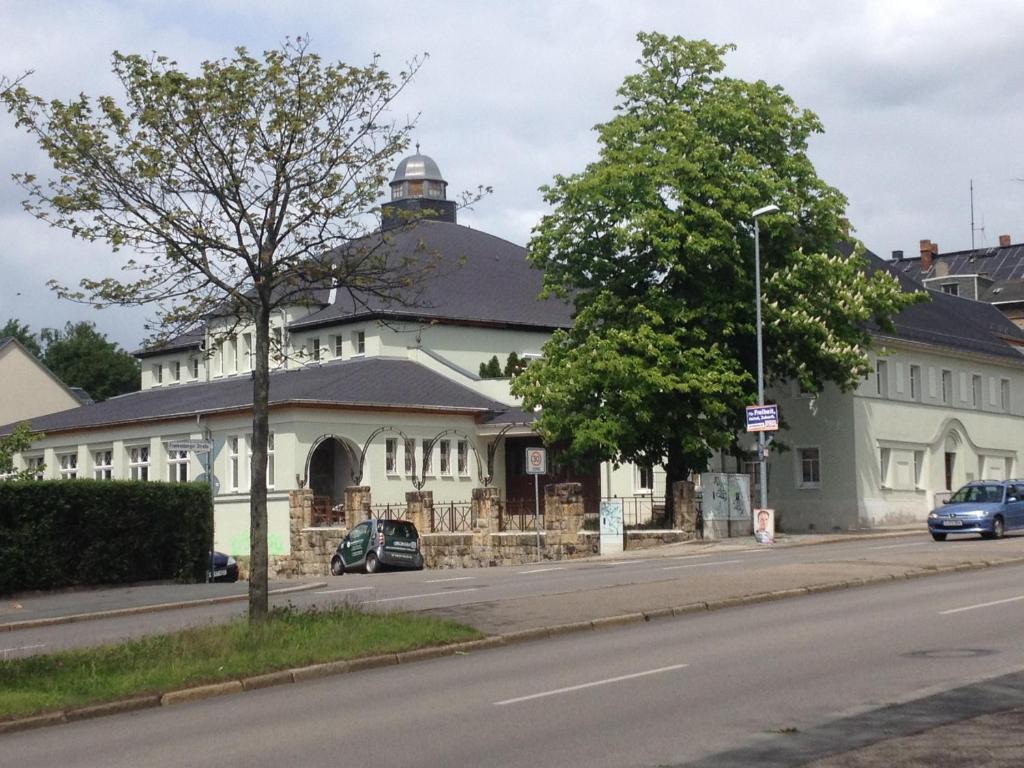 ein großes weißes Gebäude an der Straßenseite in der Unterkunft Im Ballhaus Neuhilbersdorf in Chemnitz