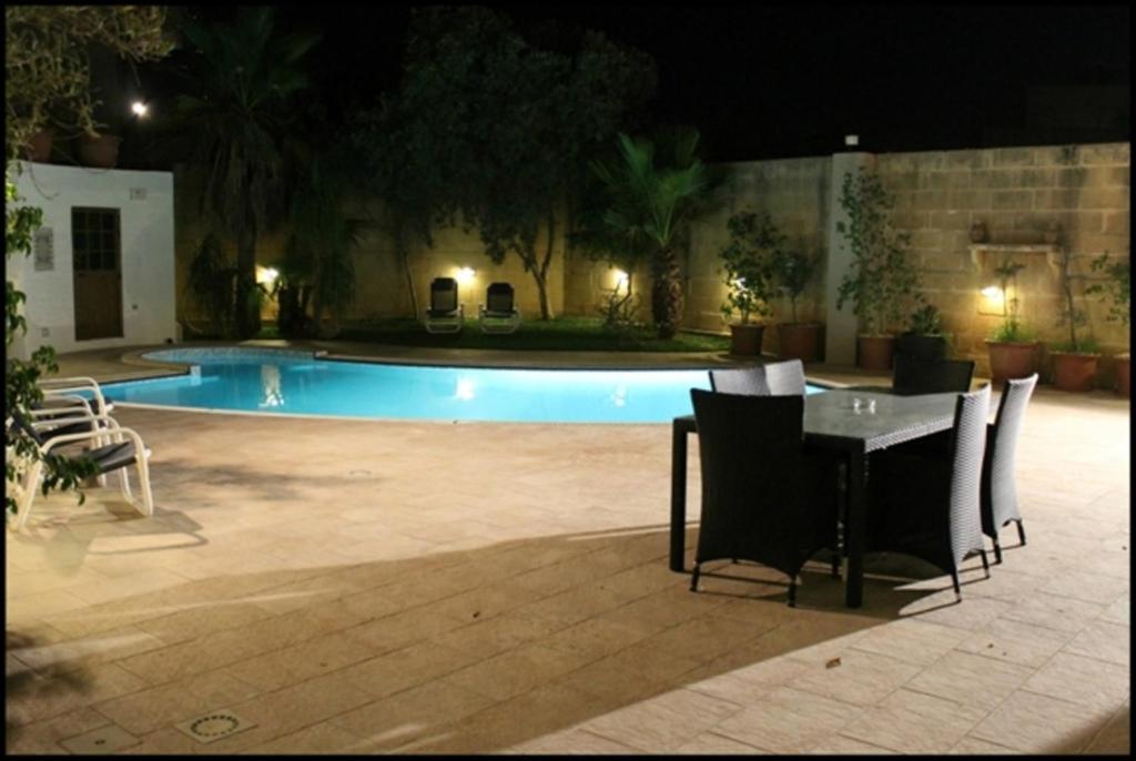 a table and chairs in front of a pool at night at Malta Villa in Naxxar