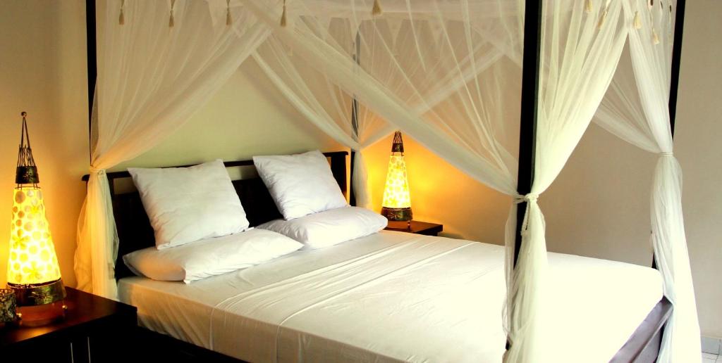 a bedroom with a canopy bed with white pillows at Latugu Homestay Ubud in Ubud