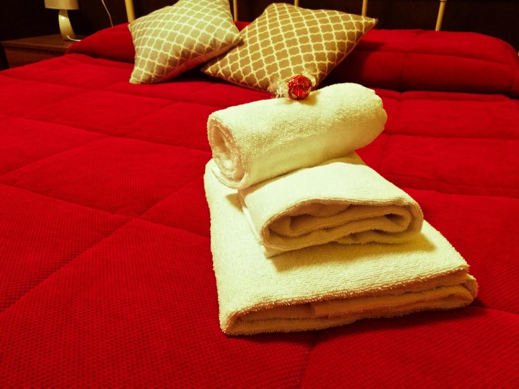 una pila de toallas en una cama roja en Garden Inn, en Capua