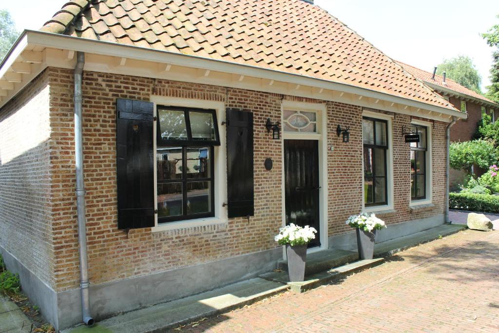 una casa de ladrillo con una puerta y ventanas negras en 't Stee fan Anne P., en Rottevalle