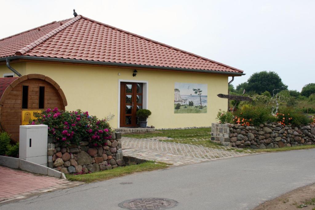 ein kleines gelbes Haus mit einer Steinmauer in der Unterkunft Haus Wildrose in Dranske