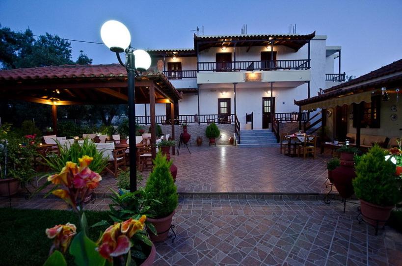 a large building with a patio with tables and chairs at Studios Filippos in Skopelos Town