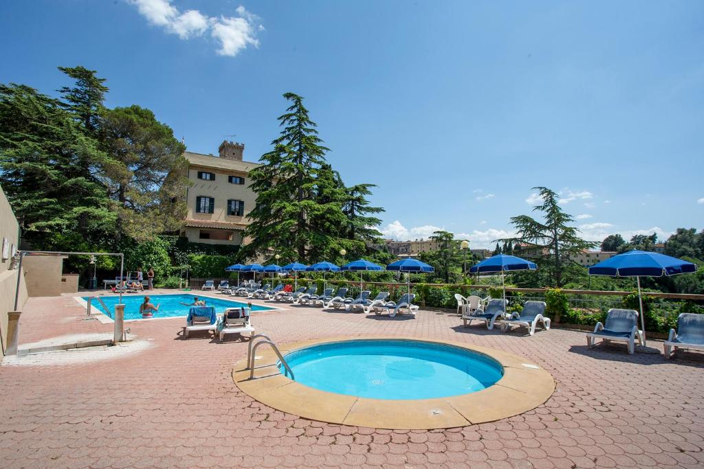 una gran piscina con sillas y sombrillas en Residence Villa Elena en Guardistallo