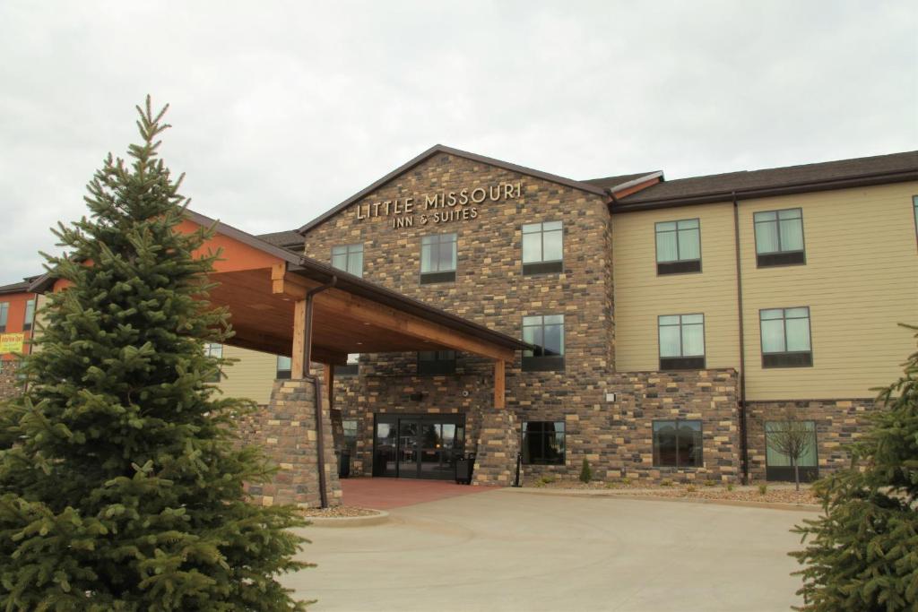 a building with a christmas tree in front of it at Little Missouri Inn & Suites New Town in New Town