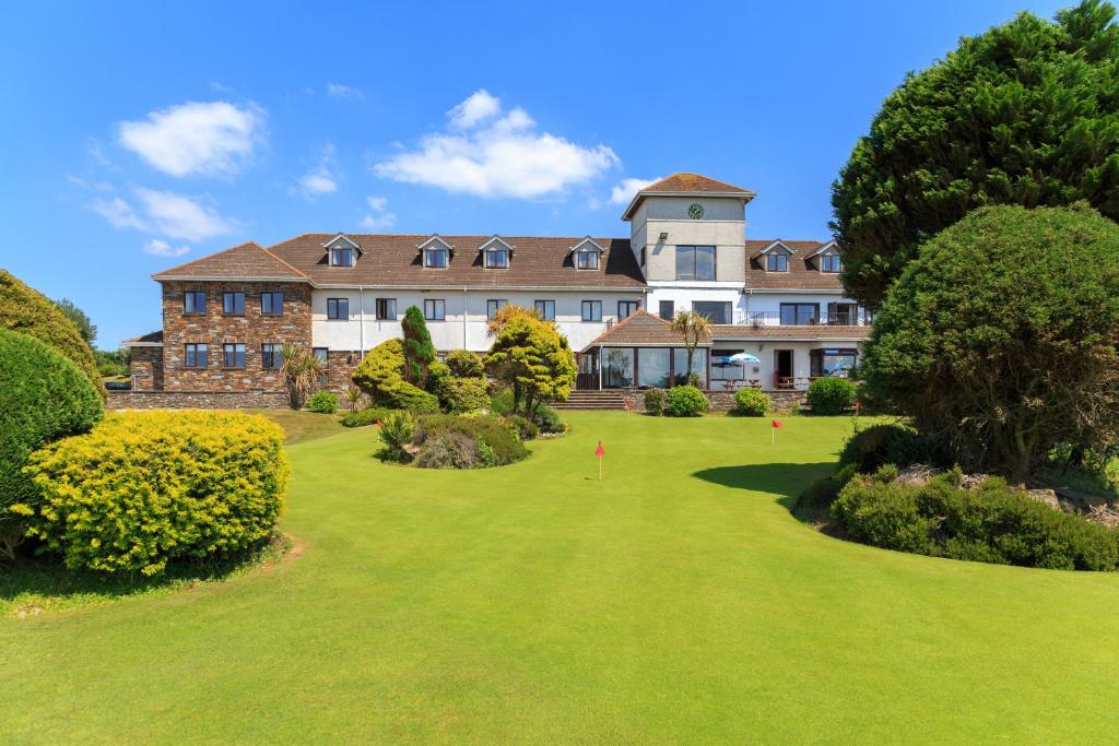 an exterior view of a large building with a green yard at Bowood Park Hotel in Camelford