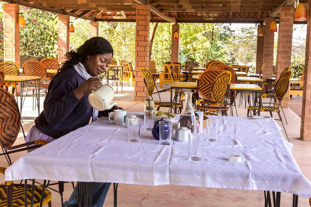 a woman is standing at a table with a pot at Sougri Doogo in Loumbila
