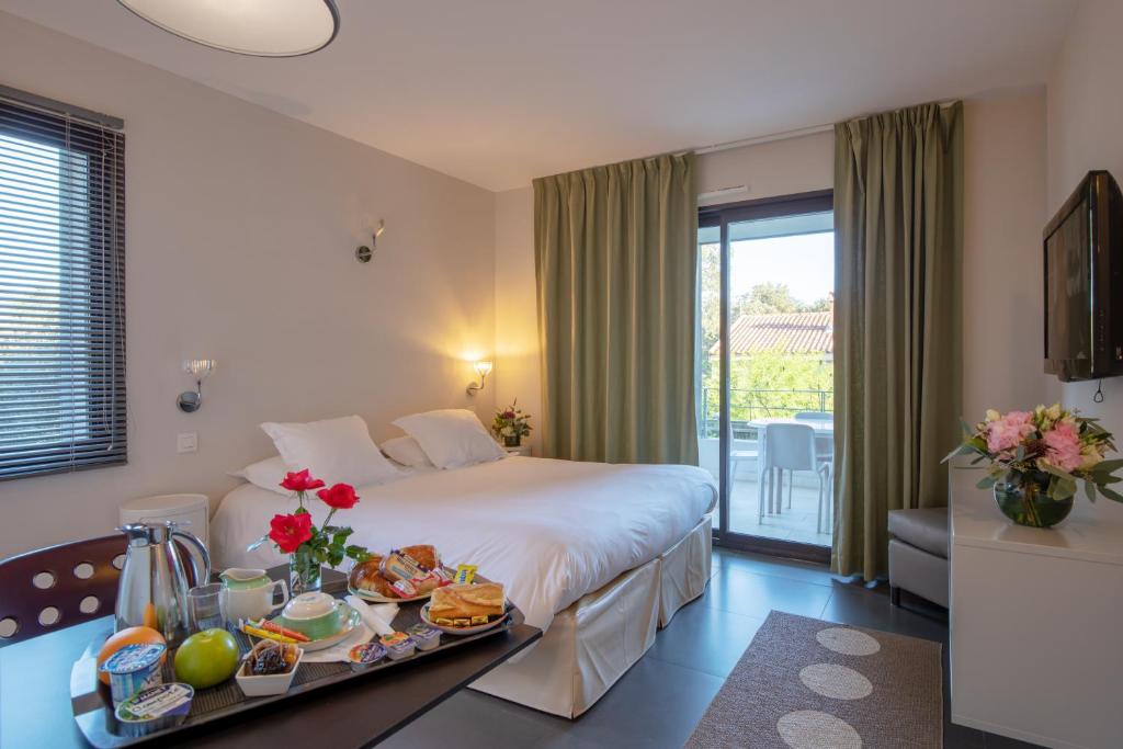 um quarto de hotel com uma cama com uma bandeja de comida em Résidence Hôtelière Alcyon em Porto-Vecchio