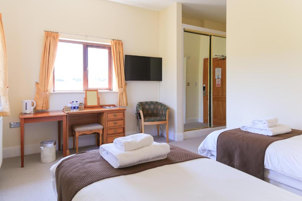 a hotel room with two beds and a desk and a window at Bowood Park Hotel in Camelford