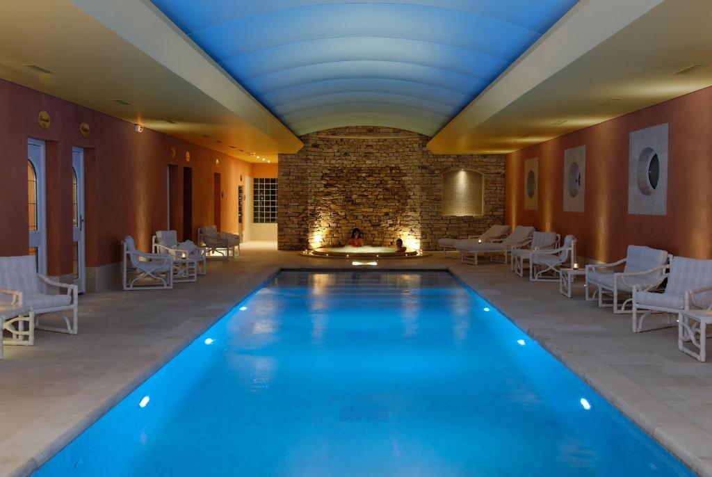 a large room with a pool, chairs, and a tub at Auberge de Cassagne & Spa in Le Pontet
