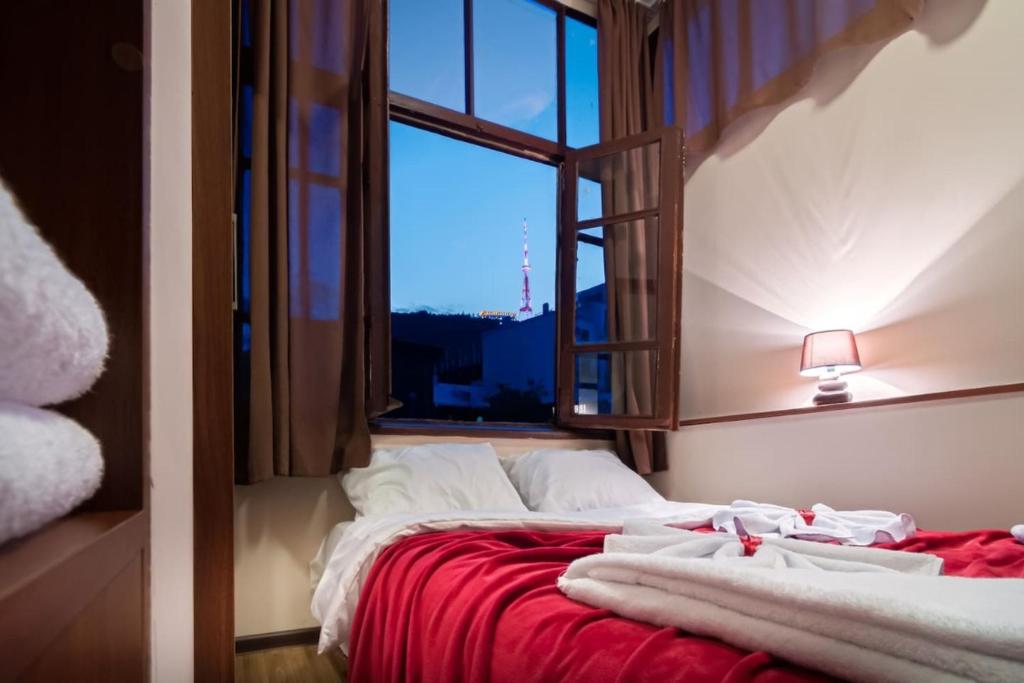 a bedroom with a bed with a red blanket and a window at Old Tbilisi Flavor for you2 in Tbilisi City