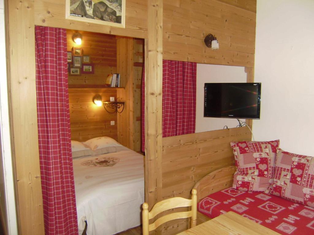 a bedroom with a bed and a tv and a chair at Studio Les Drus / Studio du Brévent in Chamonix-Mont-Blanc