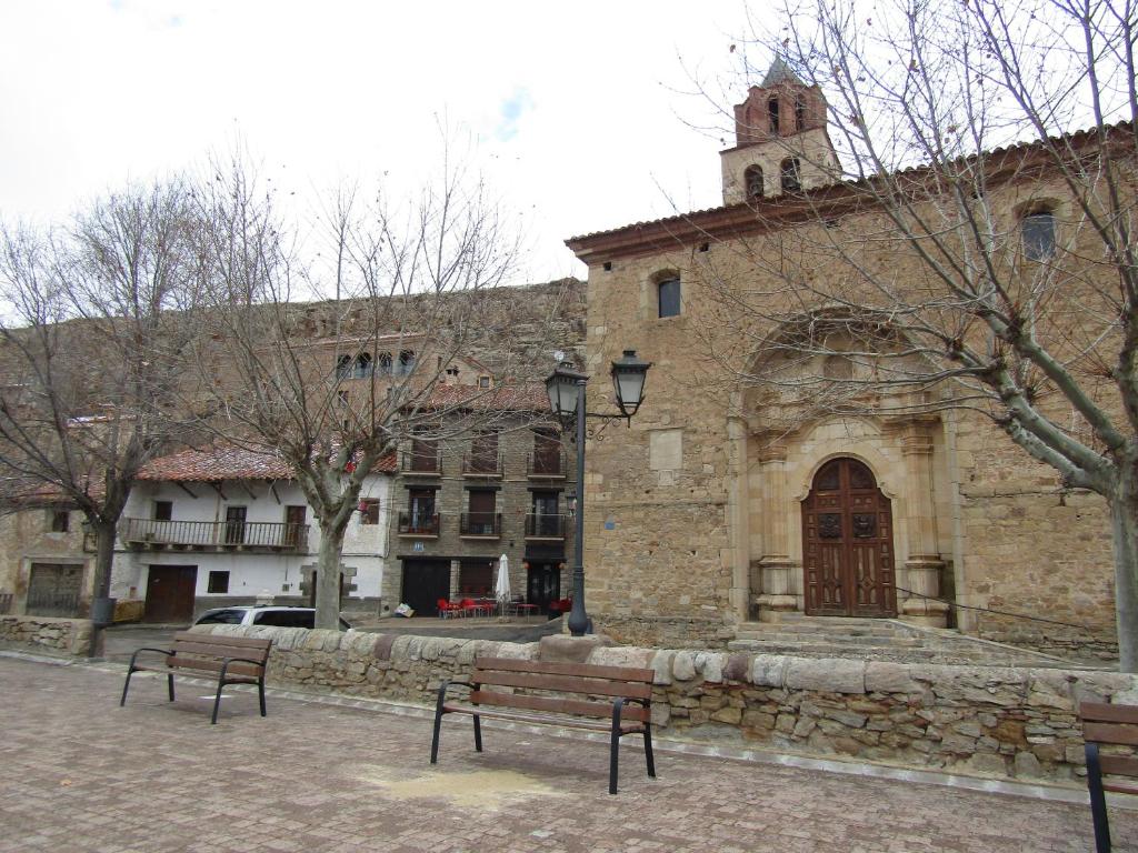 a stone building with two benches in front of it at Hostal Paquita in Allepuz