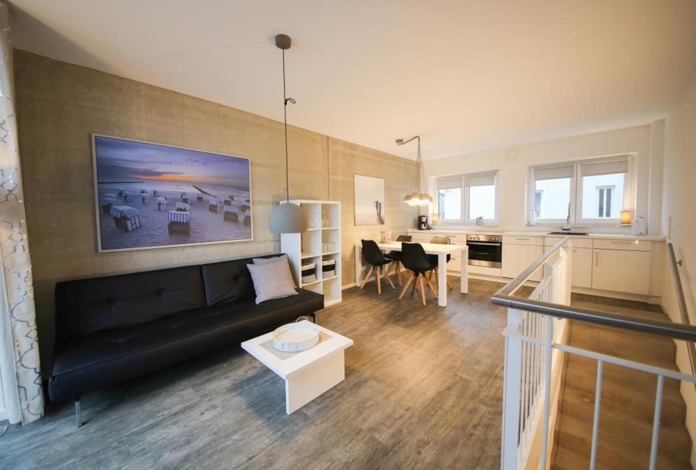 ein Wohnzimmer mit einem schwarzen Sofa und einem Tisch in der Unterkunft Ferienwohnung Hafenkante in Niendorf