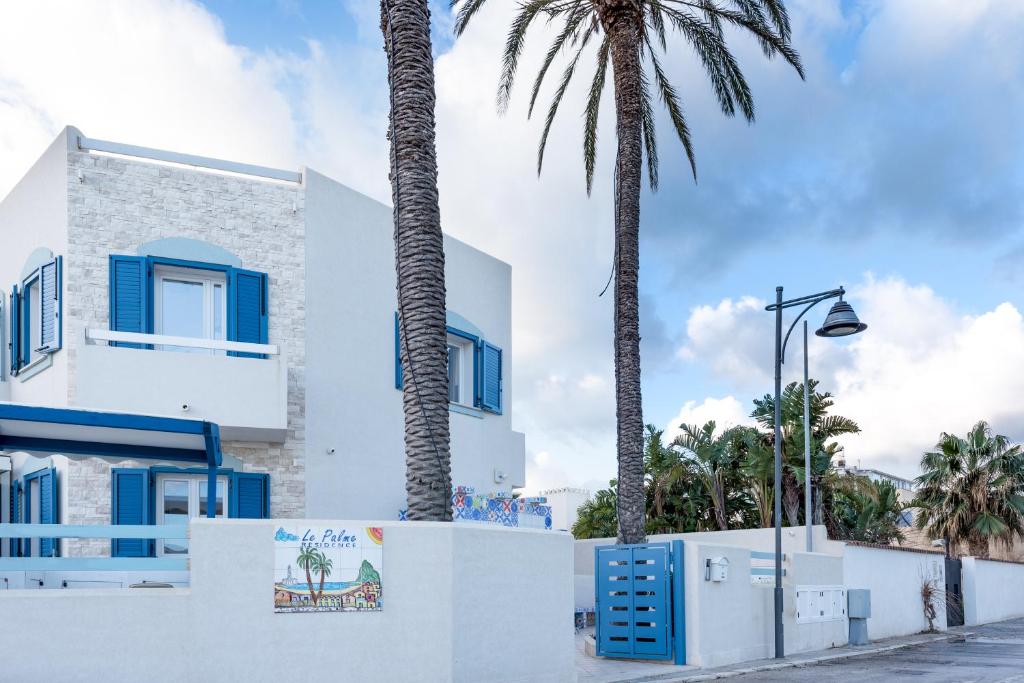 een wit gebouw met palmbomen ervoor bij Residence Le Palme in San Vito lo Capo
