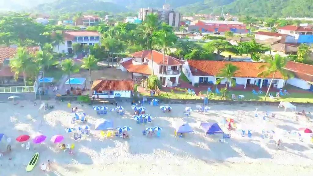 un gruppo di persone su una spiaggia con ombrelloni di Hotel Porto do Eixo Ubatuba a Ubatuba