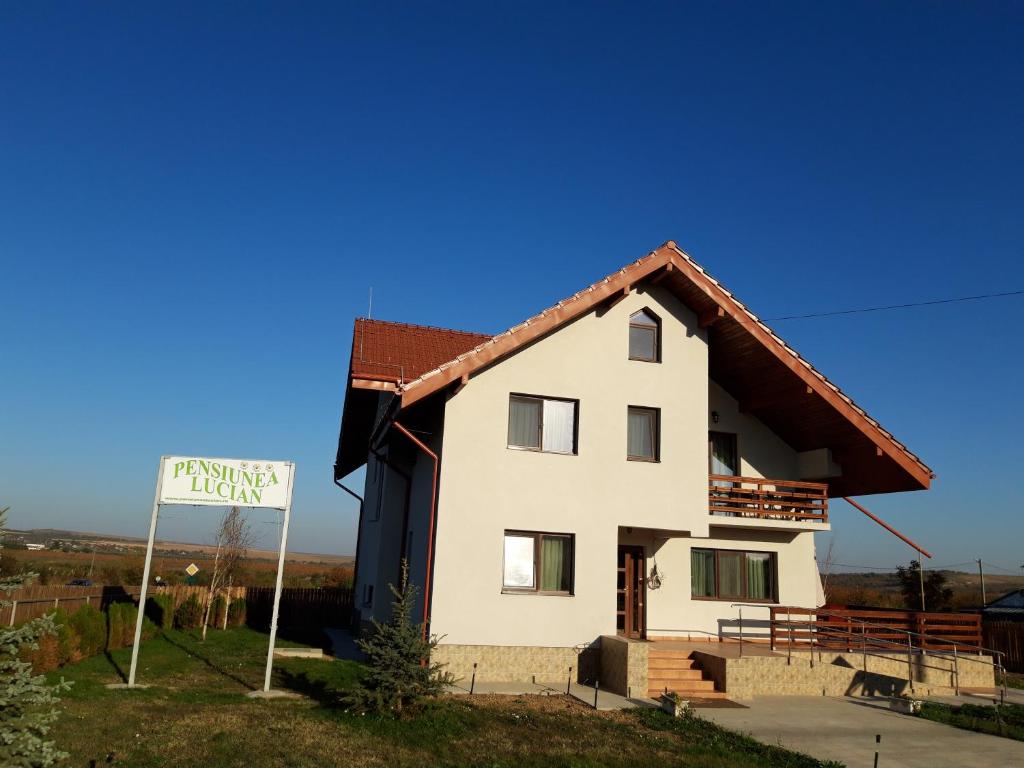 une maison blanche avec un panneau devant elle dans l'établissement Pensiunea Lucian, à Bălţaţi