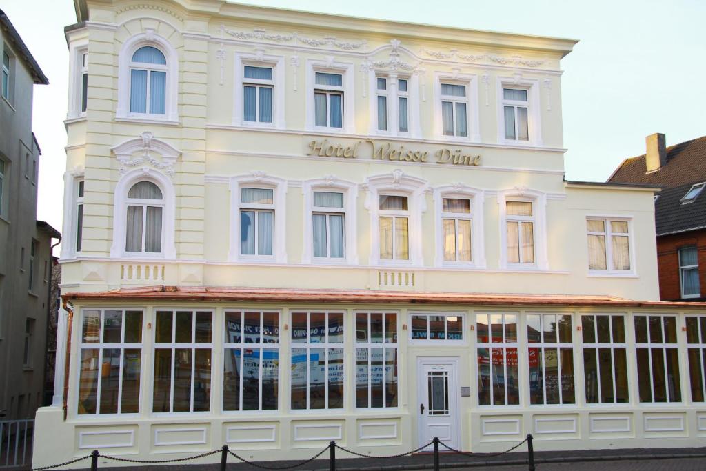 a large white building with a store front at Hotel Weisse Düne in Borkum