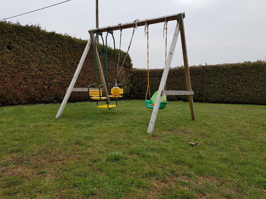 zwei Schaukeln in einem Hof mit Gras und Hecke in der Unterkunft Apartmaji Tisa in Moravske-Toplice