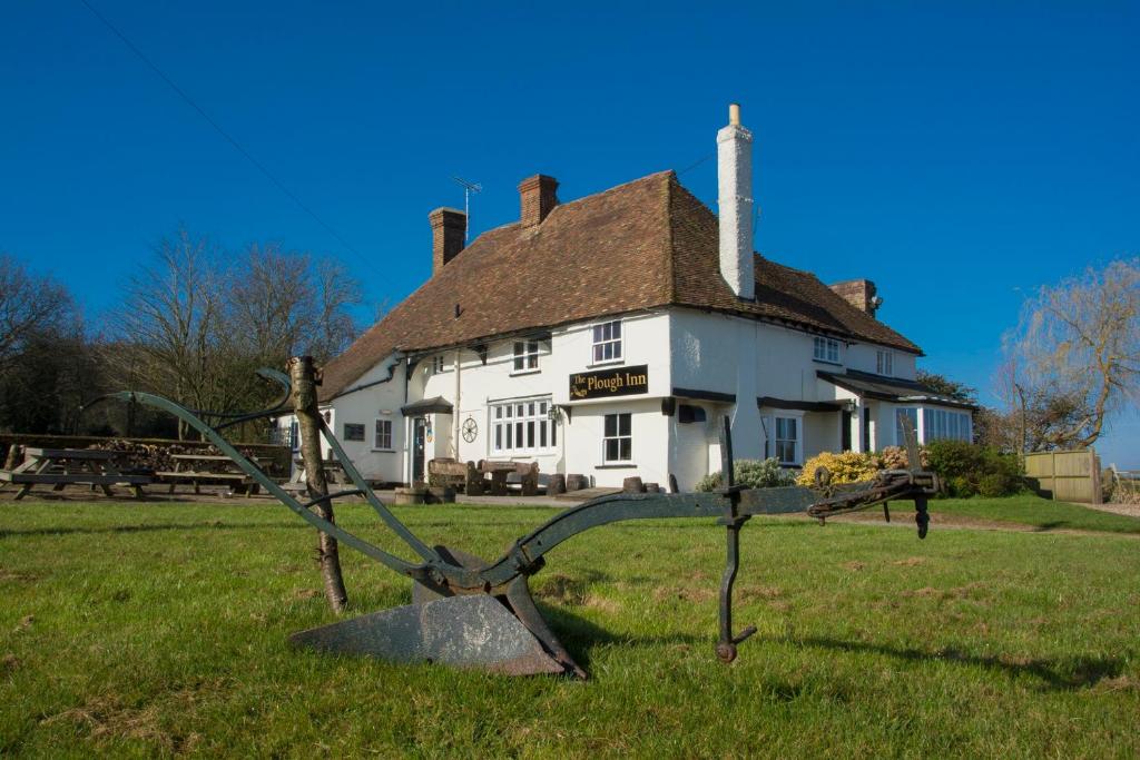 een oud huis met een standbeeld ervoor bij The Plough Inn in Stalisfield