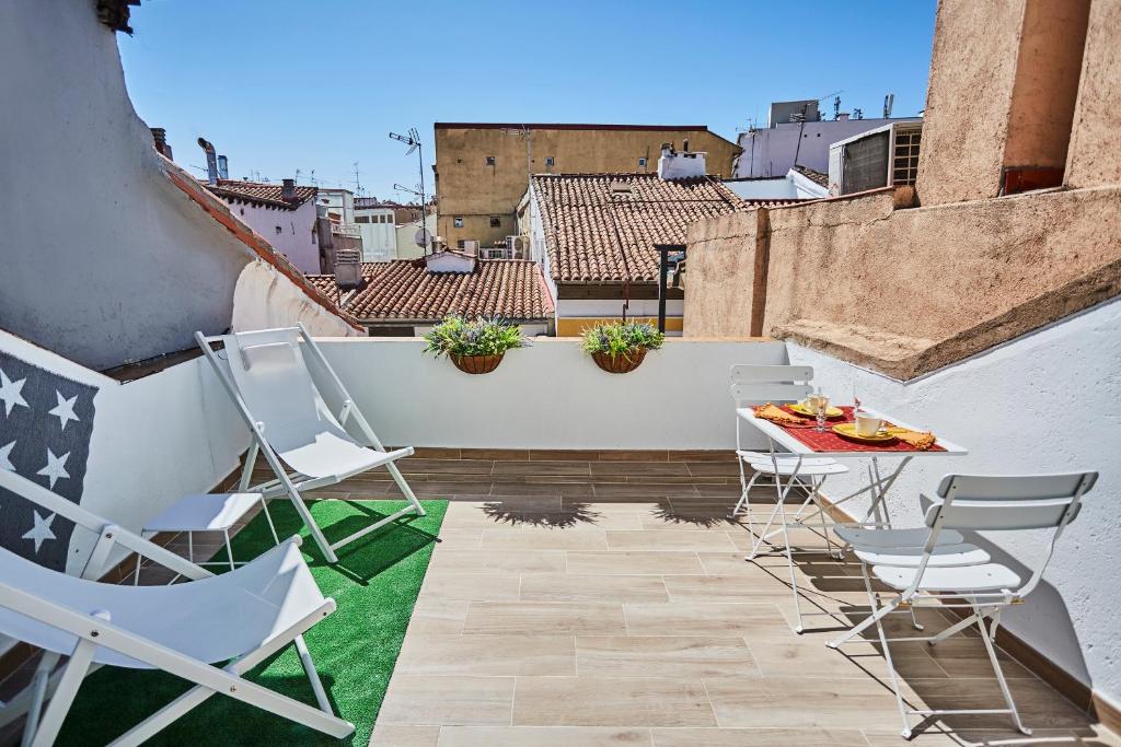 a patio with chairs and a table on a balcony at Ático duplex con terraza en puro centro, 2 a 8 pax in Madrid