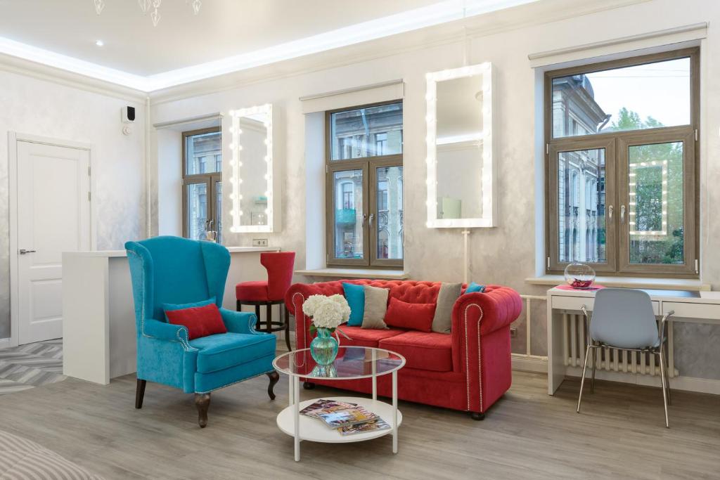 a living room with a red couch and two blue chairs at Roomburg Apartments in Saint Petersburg