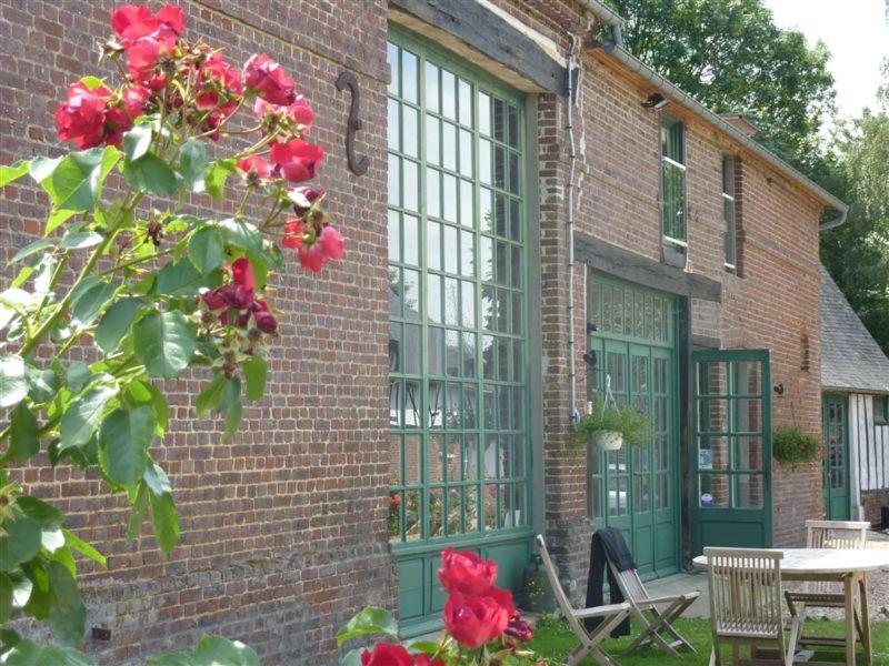 a brick building with green windows and red roses at Gît' Âne Evasion in Le Bec-Thomas