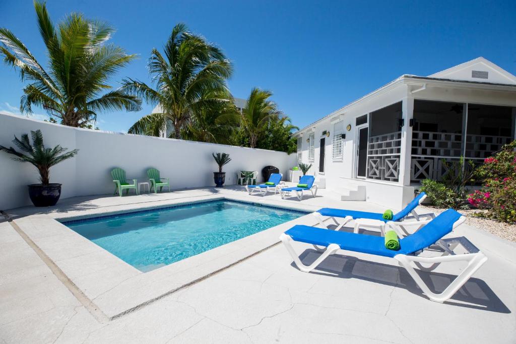 a swimming pool with two lounge chairs and a house at 3 Bedroom Villas of Elephant Walk in Grace Bay