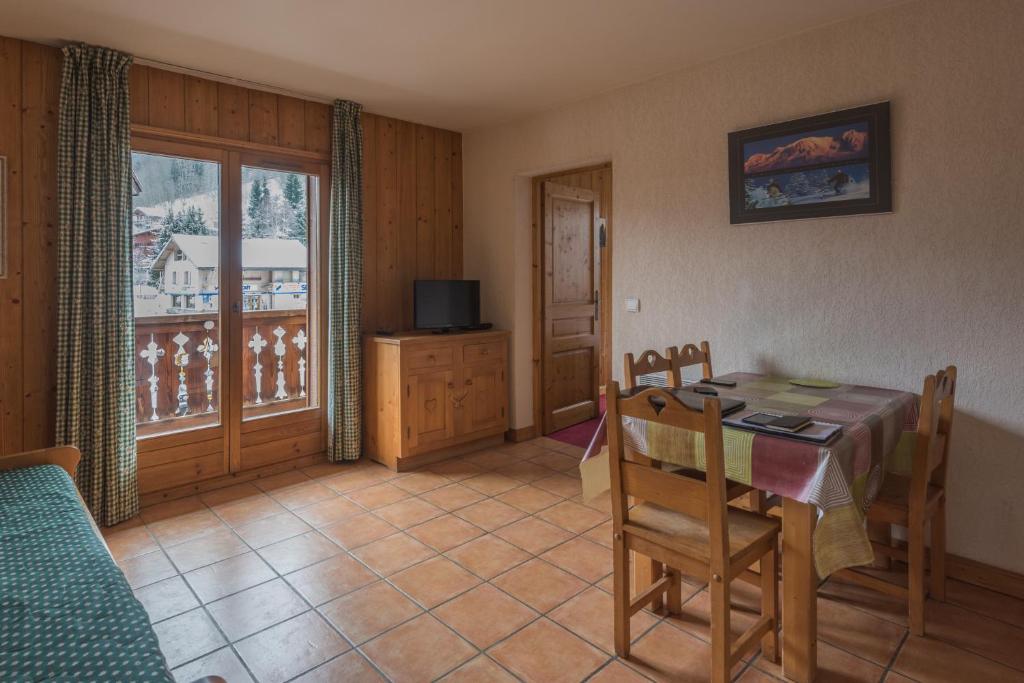 ein Esszimmer mit einem Tisch, Stühlen und einem Fenster in der Unterkunft appartement T2 LES HOUCHES Pied des Pistes in Les Houches