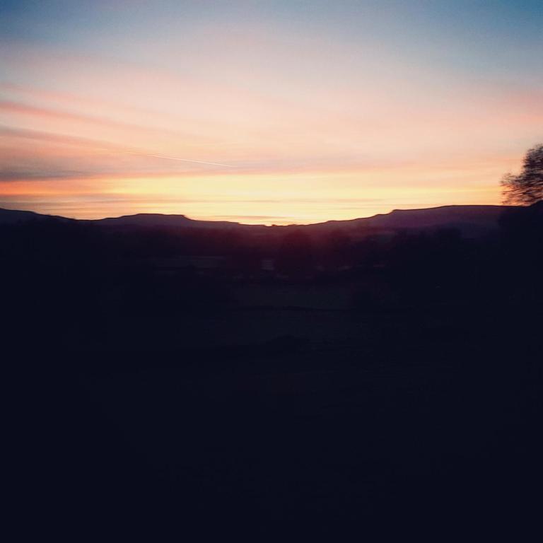 a sunset over the mountains with the sky at Wensleydale Glamping Pods in Redmire