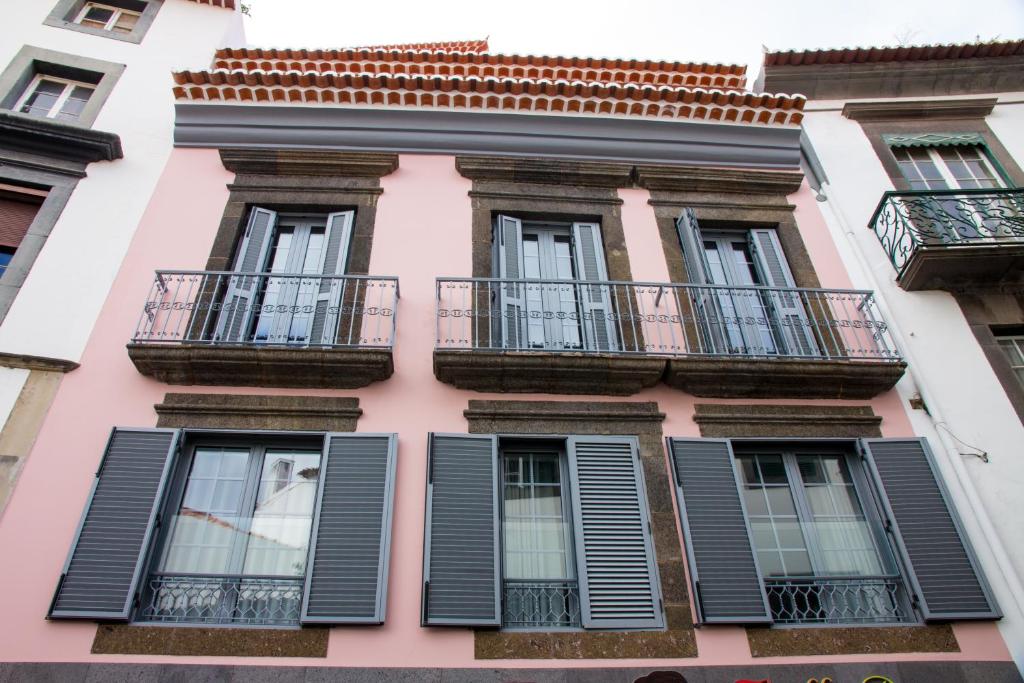 un edificio rosa con ventanas y balcones con persianas negras en Apartamentos Funchal by Petit Hotels, en Funchal