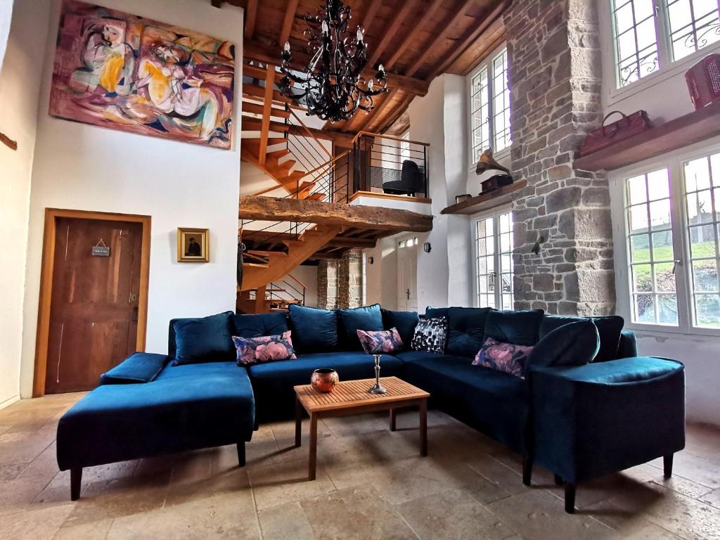 een woonkamer met een blauwe bank en een tafel bij Domaine LVD avec SPA, bois et rivière privée in La Bloutière