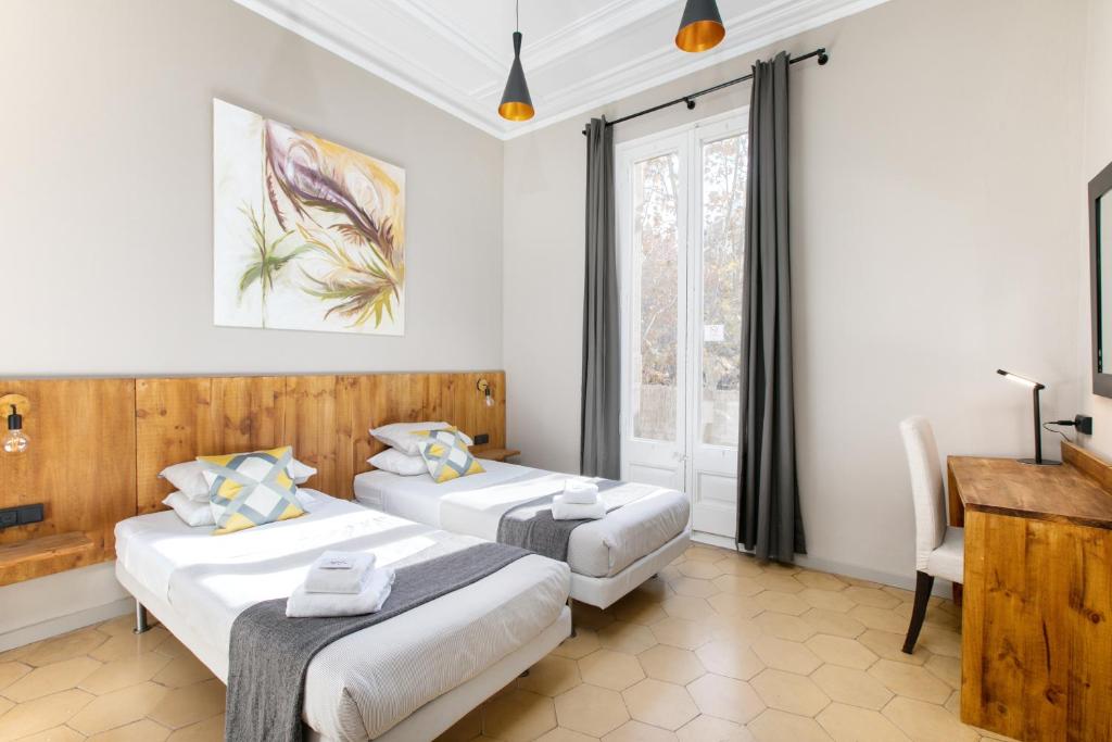 Habitación con 2 camas, escritorio y ventana. en Jardinets Guest House, en Barcelona