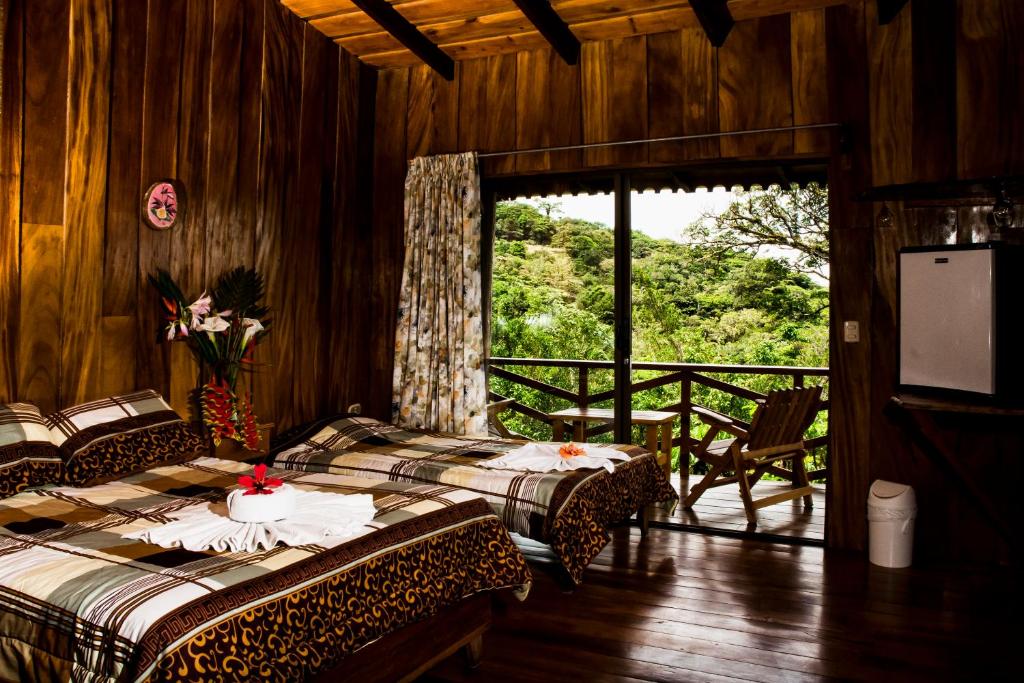 Cette chambre comprend deux lits et un balcon avec vue. dans l'établissement Cabinas Capulin & Farm, à Monteverde Costa Rica